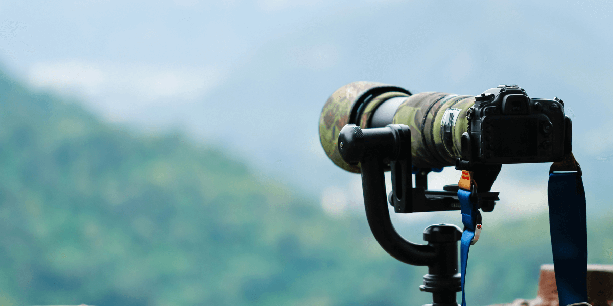 A camera mounted on a tripod facing towards the mountain.