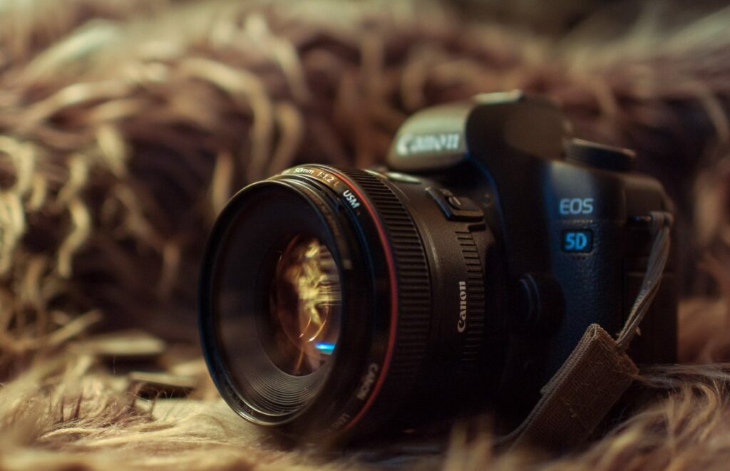 the-camera-with-an-open-lens-stands-on-a-fluffy-background