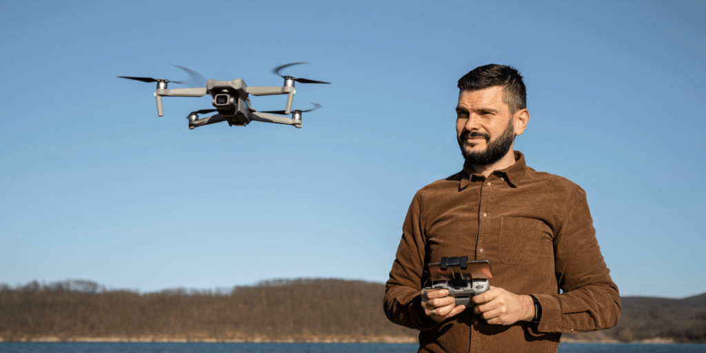 A man wearing a brown shirt focused on flying a drone outdoors.